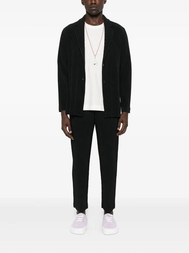 Person wearing a black blazer, white shirt, black pants, and white sneakers on a white background