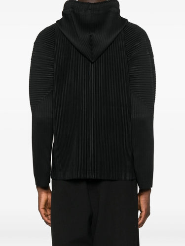 Person wearing a black ribbed sweater on a white background