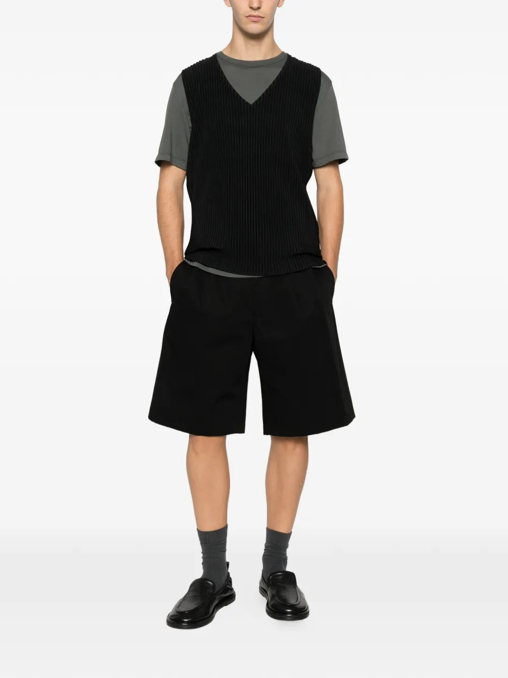 Someone wearing the black plissé vest from Homme Plissé Issey Miyake on a white background.
