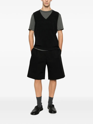Someone wearing the black plissé vest from Homme Plissé Issey Miyake on a white background.