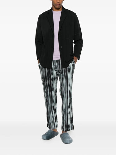 Someone wearing the black blazer with large plissé from Homme Plissé Issey Miyake on a white background.