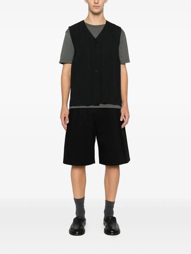 Someone wearing the black plissé vest with front button closure from Homme Plissé Issey Miyake on a white background.