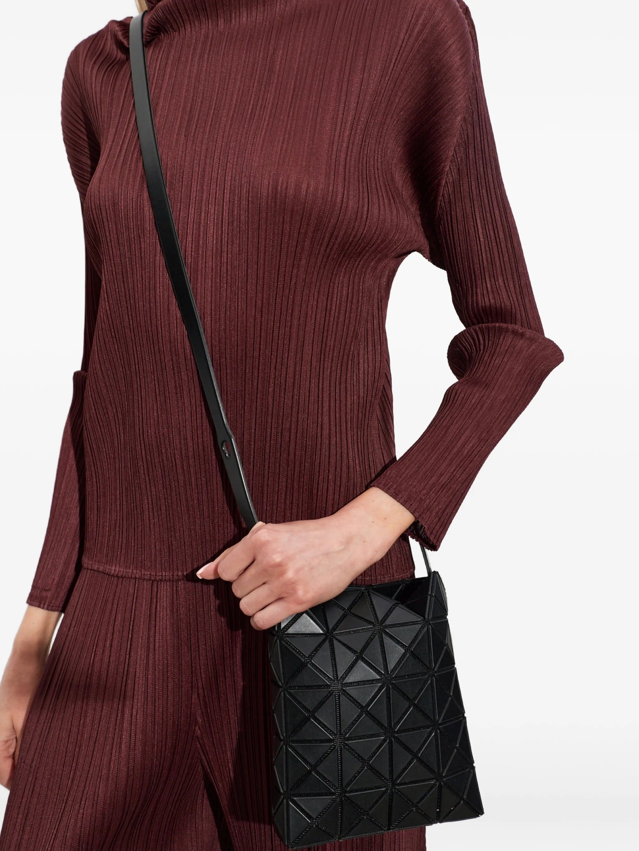 Model wearing Bao Bao Issey Miyake Prism Matte Shoulder Bag in matte black as a crossbody bag with signature geometric panel construction