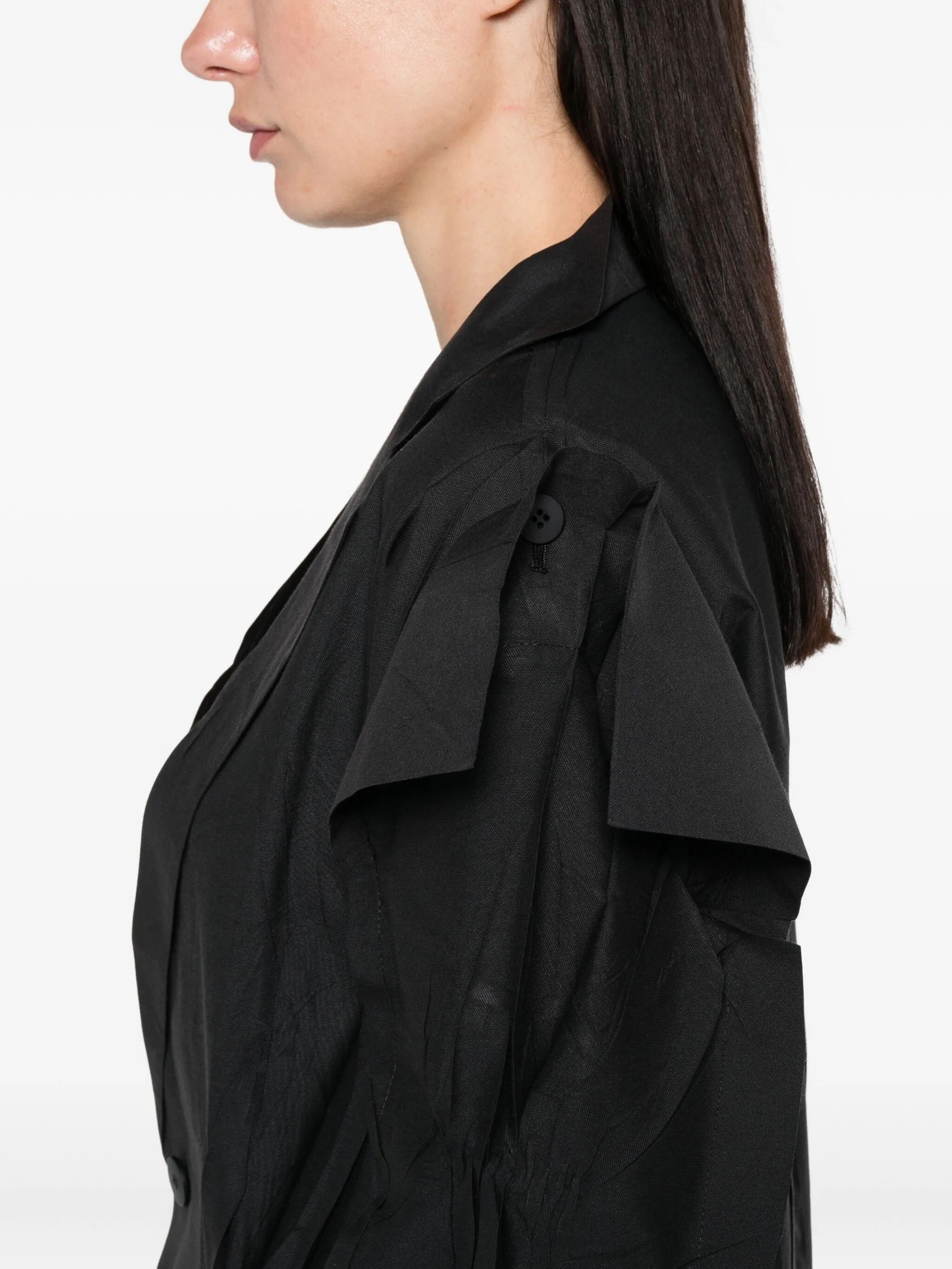 Black shirt with ruffled sleeves worn by a person on a white background