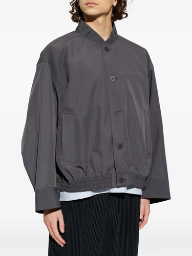 Close-up front view of the male model wearing the blouson, highlighting the high neckline, button fastening, and textured dark grey fabric.