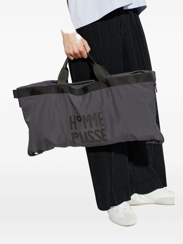 The January Carrier Carried Blouson folded, zipped, and secured with snap-buttons into a compact carry-on bag for portability.