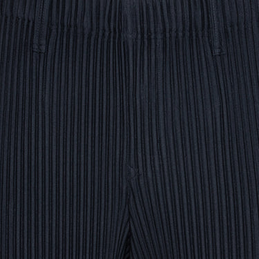 Close-up of the navy plissé pants with straight legs from Issey Miyake Homme Plissé