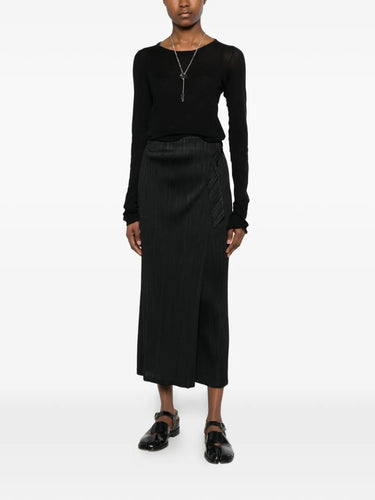 Model wearing the February SS26 Facade Pants in Black black pleated straight-leg pants with wrap detail and belt at mid-rise waist, front view – Issey Miyake Pleats Please