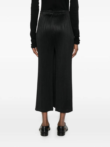 Model wearing the February SS26 Facade Pants in Black black pleated straight-leg pants with elasticated waistband, back view – Issey Miyake Pleats Please