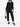 Woman wearing a black pleated outfit from Pleats Please Issey Miyake on a white background