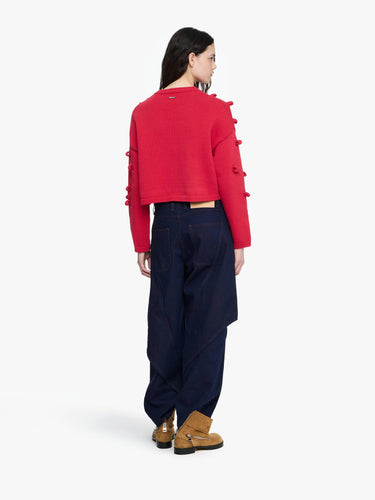 Person wearing a red cropped jacket and navy pants on a white background