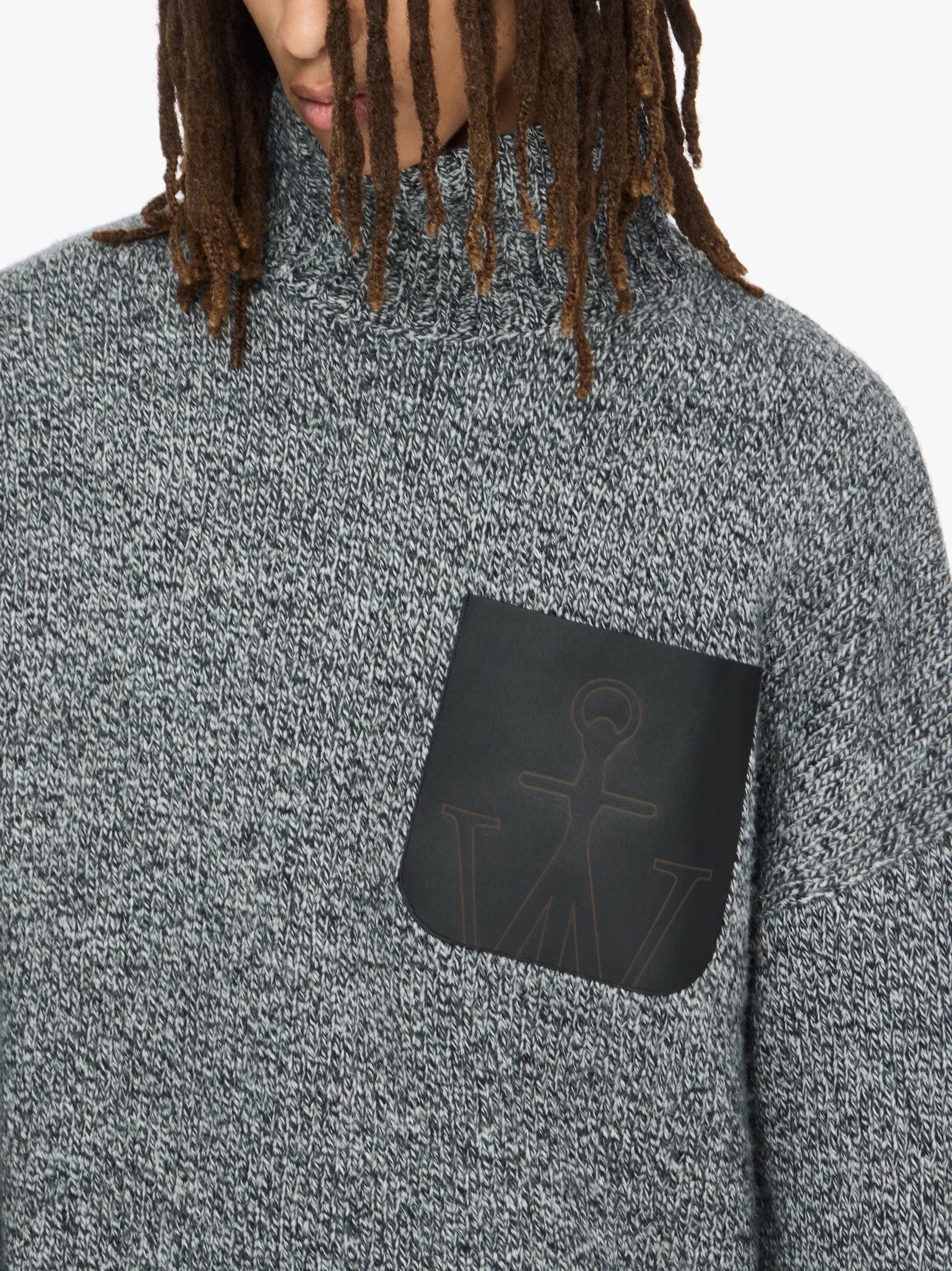 Person wearing a gray turtleneck sweater with a black patch on a white background