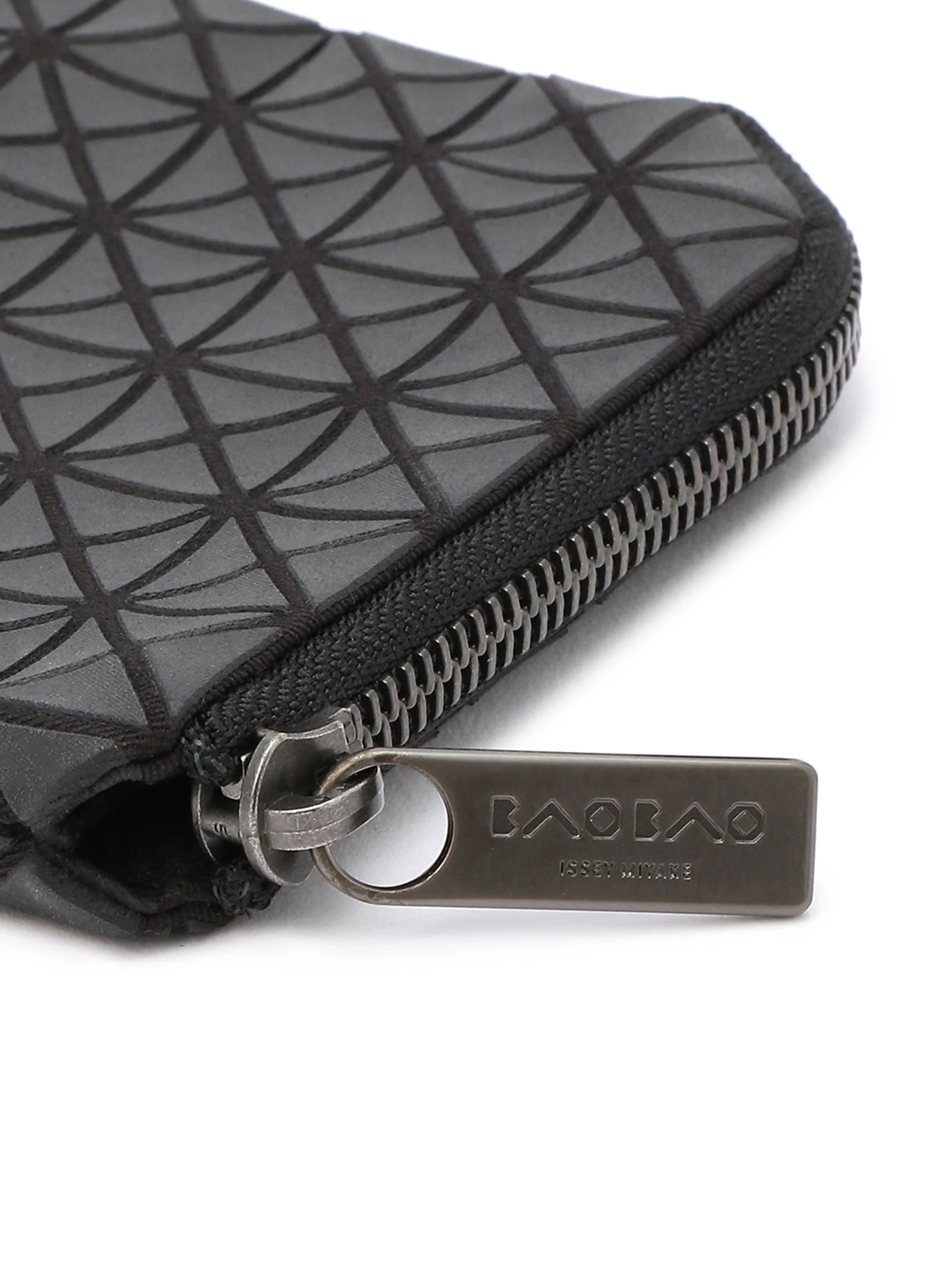 Close-up of Bao Bao Issey Miyake Kuro Clam Wallet in matte black showing triangular panel texture, metal zip closure and logo pull tab