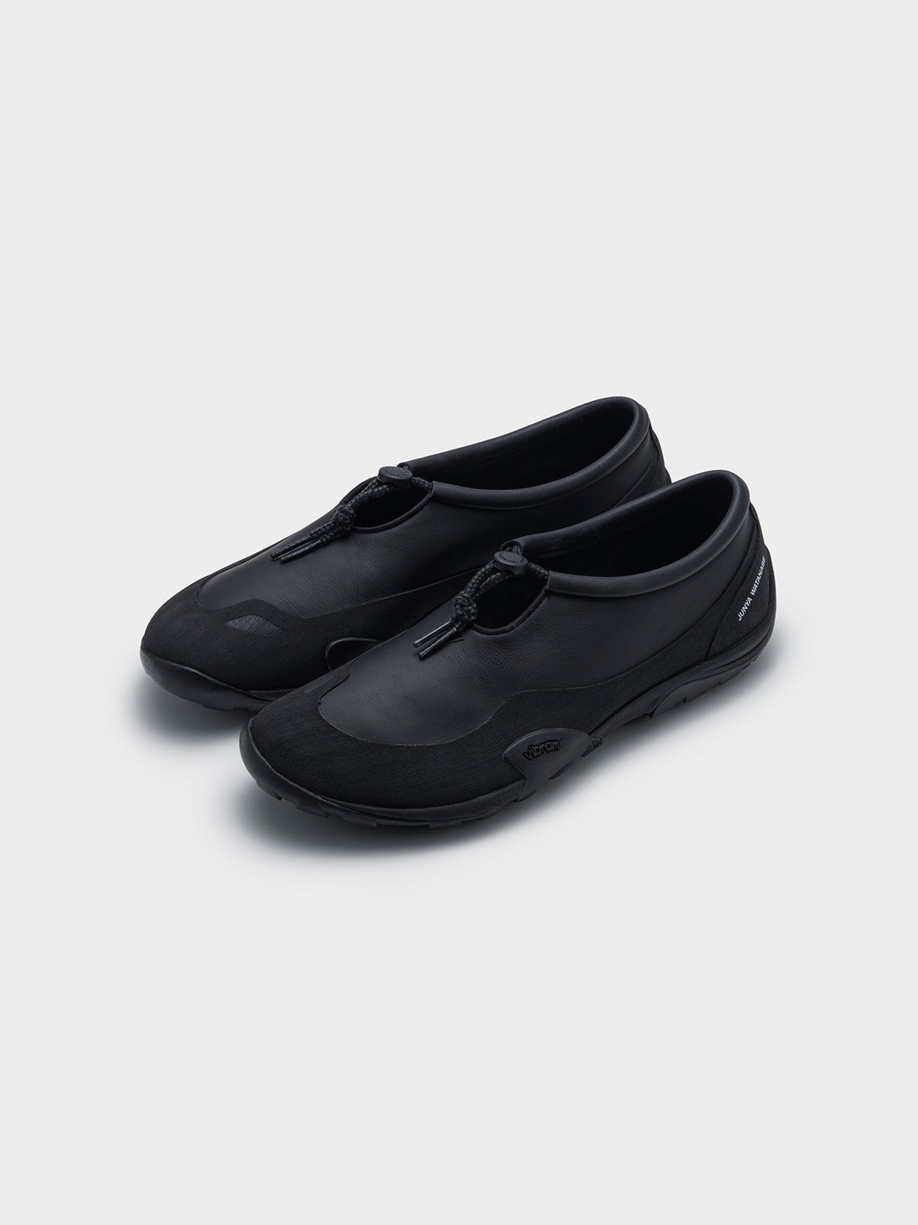 Junya Watanabe x New Balance MT10T sneakers in black, three-quarter front view of pair, rubber mudguard and toggle lace detail