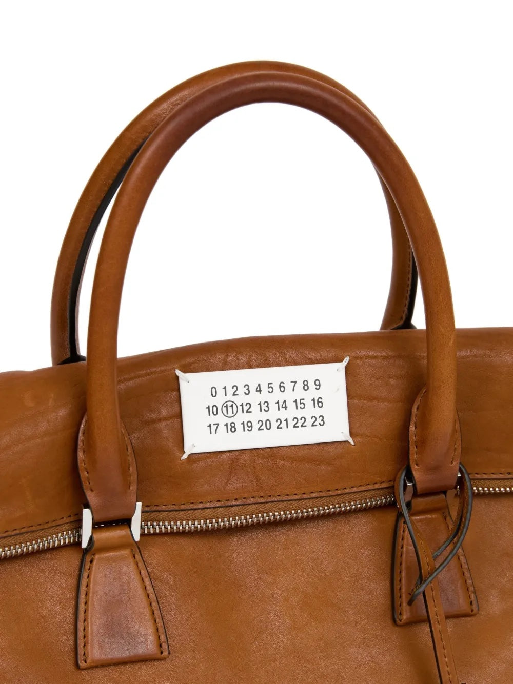A close-up of a brown 5AC leather bag from Maison Margiela on a white background.