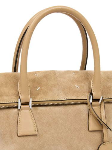 Close-up of the leather top handles and attached key charm on the camel suede 5AC Soft Medium bag with the signature four white stitches.