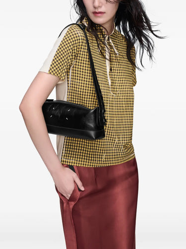 Model wearing Maison Margiela Baguette Small Bag in Black/Black, styled over the shoulder, showing the small structured silhouette and metallic hardware.