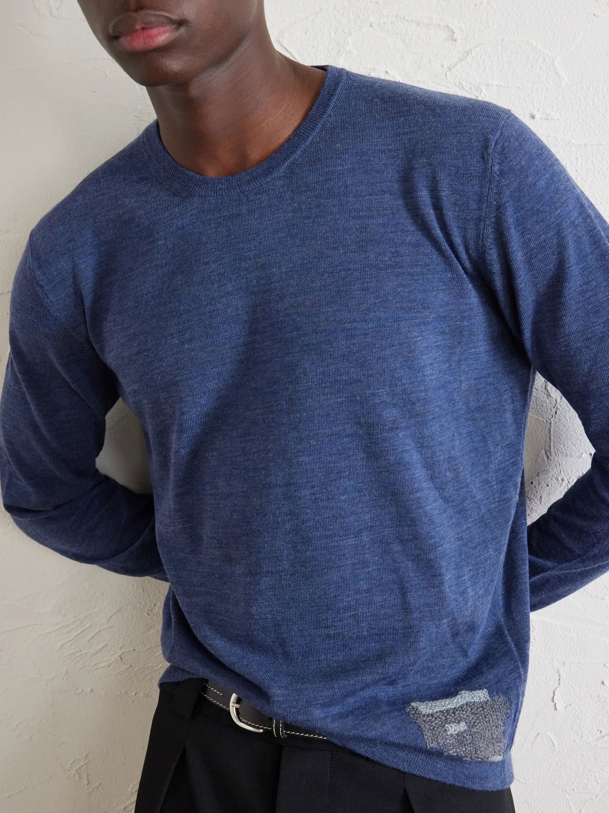 Model wearing the Maison Margiela Crewneck in Blue, showing the straight fit, fine knitted texture and distressed patch detail at the lower hem.