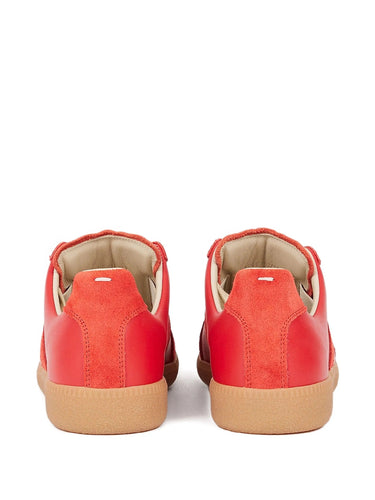 Pair of red sneakers with brown soles on a white background