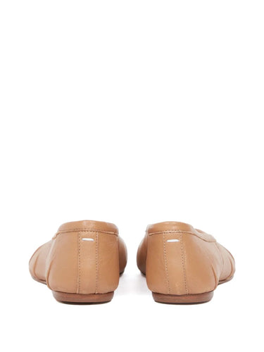 Pair of tan leather flats on a white background