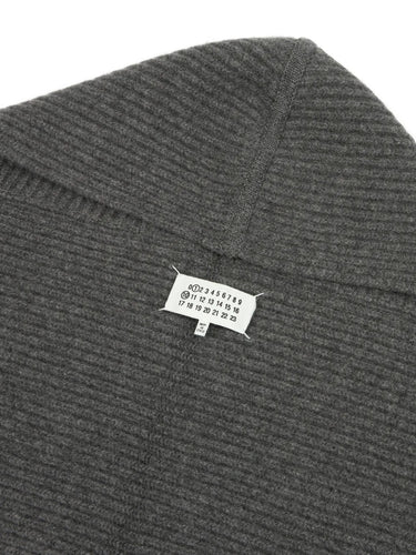 Close-up front view of the dark grey Maison Margiela hooded scarf, showing the ribbed knit fabric and the Maison Margiela brand tag.