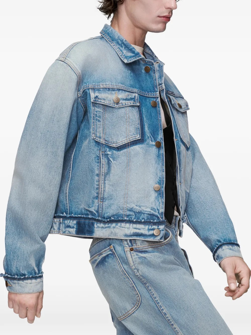 Close-up side view of the model wearing the washed blue denim Maison Margiela jacket, focusing on the long sleeves, distressed detailing, and cropped hem.