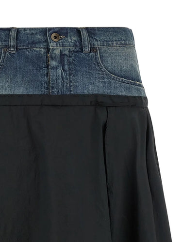 Close-up of a black skirt with a blue denim top section on a white background