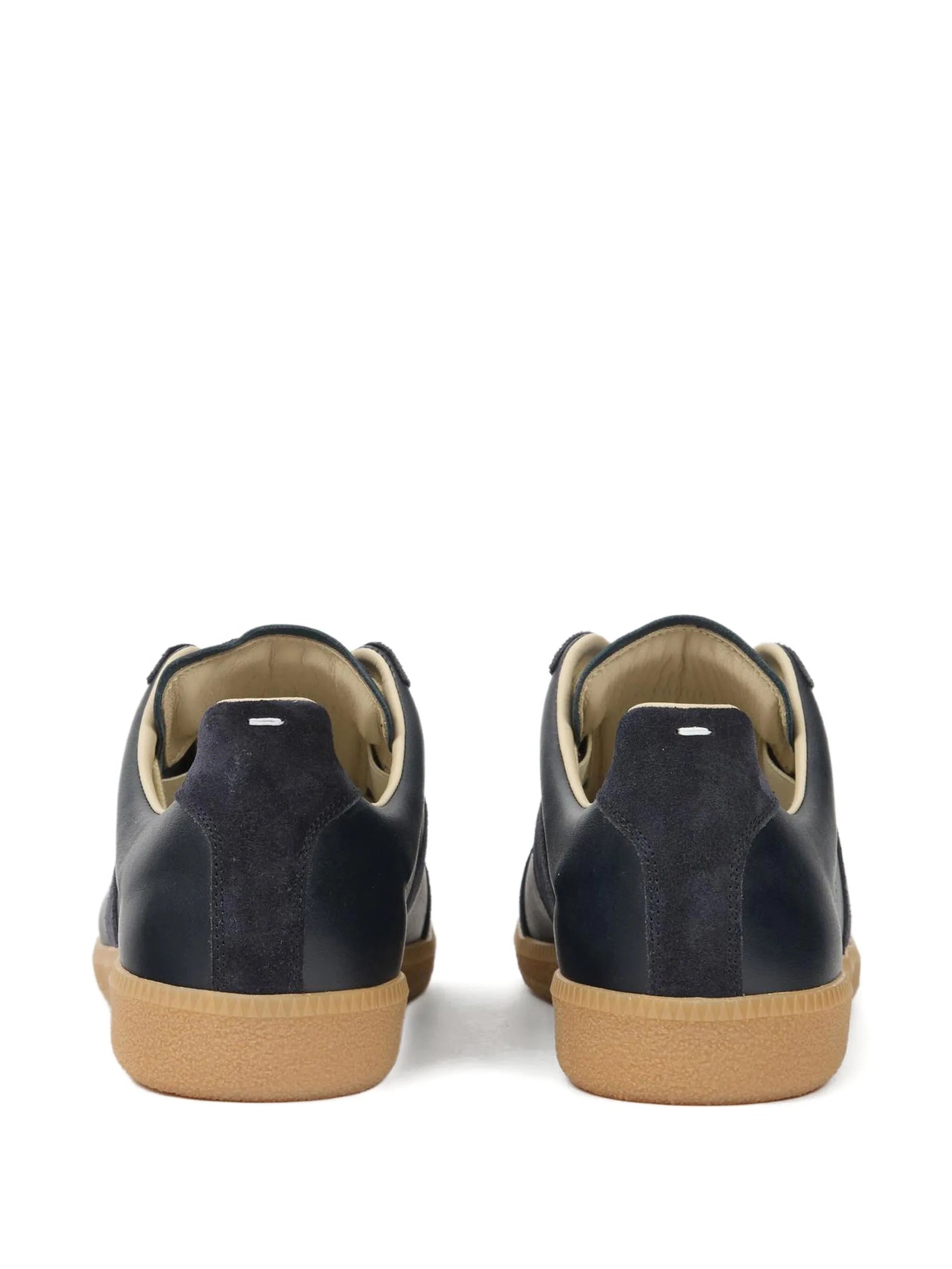 Back view of dark navy blue leather sneakers with white stitch detail on a white background