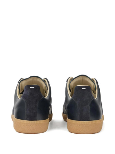 Back view of dark navy blue leather sneakers with white stitch detail on a white background