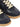 Close-up of dark navy blue leather sneakers with panel design and rubber soles on a white background