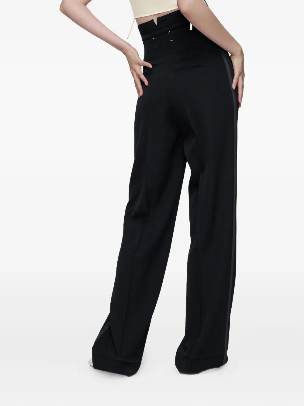 Back view of the model wearing the black Maison Margiela women’s pants, showing the tailored back and minimalist silhouette.