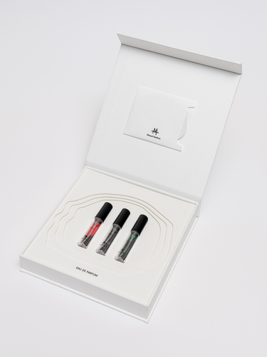 Three small perfume bottles with black caps on a white background