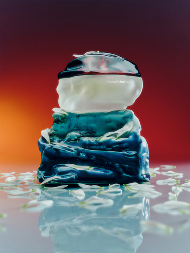 Perfume bottle by Manuel Mathieu on a reflective surface with a gradient background