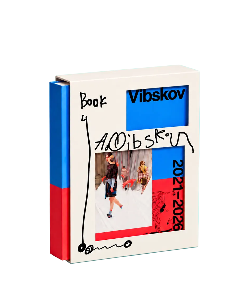 A hardcover book titled 'Vibskov' by artist Viktoria Brodskis stands upright on a light blue background. The cover is cream-colored with a collage of fashion imagery, featuring a prominent blue block, a red block, and a central photo of a model.