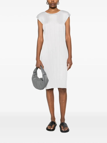 Model wearing the light grey, short sleeves, pleated dress from Pleats Please Issey Miyake on a white background