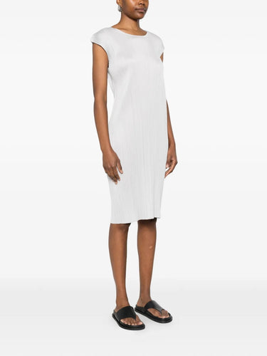 Side view of model wearing the light grey, short sleeves, pleated dress from Pleats Please Issey Miyake on a white background