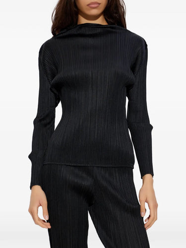 Model wearing the black pleated mock neck top with long sleeves from Pleats Please Issey Miyake on a white background
