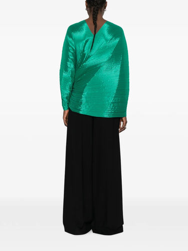 Back view of a model wearing the green pleated top called Madam T by Pleats Please Issey Miyake on a white background