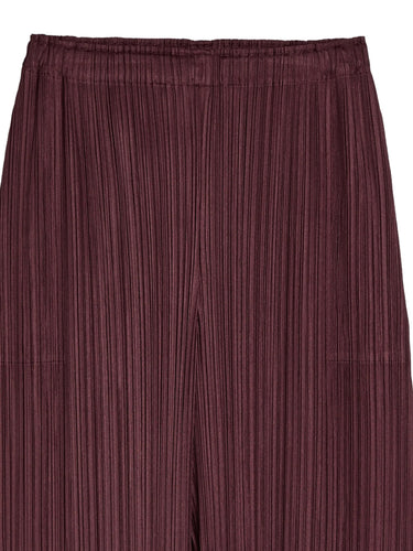 Close-up of the bordeaux pleated pants from Pleats Please Issey Miyake on a white background
