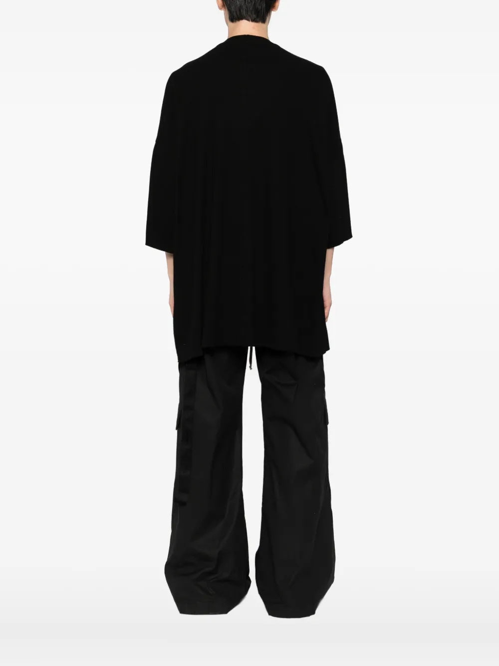 Person wearing a loose-fitting black outfit on a white background