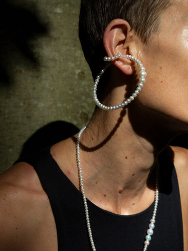 Model wearing the Drop Pearl Earcuff Double Big in Pearl/Silver from the Saskia Diez Spring Summer 2026 collection, showing the two-ring design with a large 7 cm ring and a smaller 2 cm ring connected by a drop pearl.