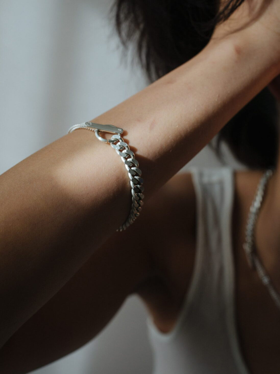 Model wearing the Grand Bracelet Mixed in Silver from the Saskia Diez Spring Summer 2026 collection on the hand, showing the bold curbed chain and toggle closure.