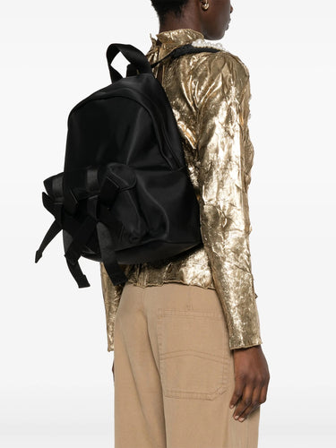Person wearing a black backpack and gold jacket on a white background