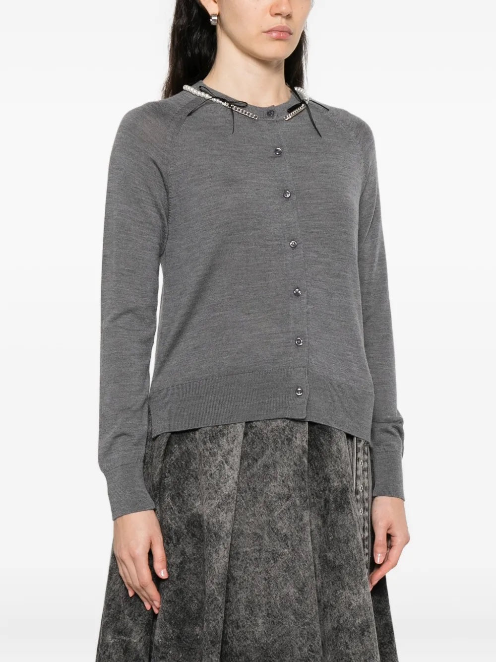 Person wearing a gray cardigan from Simone Rocha on a white background