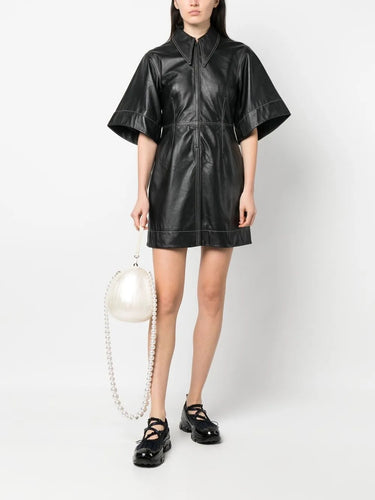 Model holding the Large Pearl Crossbody Egg Bag, showing the sculptural egg shape, glossy pearl-toned finish, and detachable pearl strap.