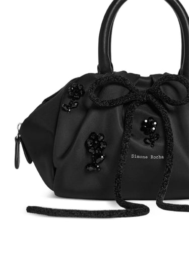Black handbag with decorative elements and 'Simone Rocha' branding on a white background