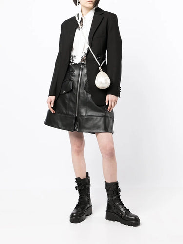 Model holding the Simone Rocha Pearl Crossbody Micro Egg Bag, showing the sculptural egg shape, pearl surface, and crossbody strap.