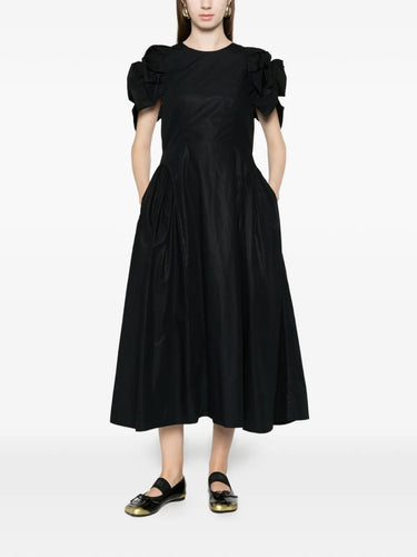 Model wearing the Simone Rocha black hip dress, shown from the front with fitted bodice, voluminous skirt, and signature puff sleeves.