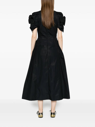 Back view of the model wearing the black cotton poplin dress, showcasing the tiered skirt and full silhouette.