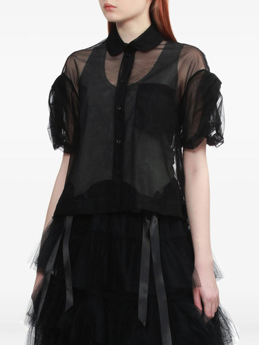 A person wearing a sheer black cropped shirt with puffy sleeves from Simone Rocha